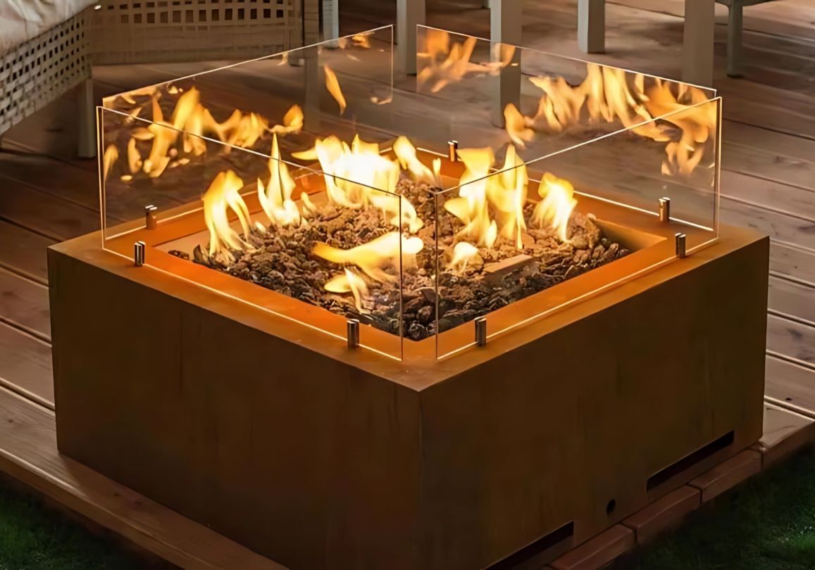 Modern outdoor gas fire pit with glass wind guard and decorative lava rocks